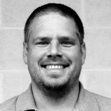 Der Mann zeigt ein breites Lächeln, während er direkt in die Kamera schaut, mit einem freundlichen und offenen Ausdruck.