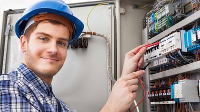 Ein junger Elektriker überprüft einen Verteilerkasten 