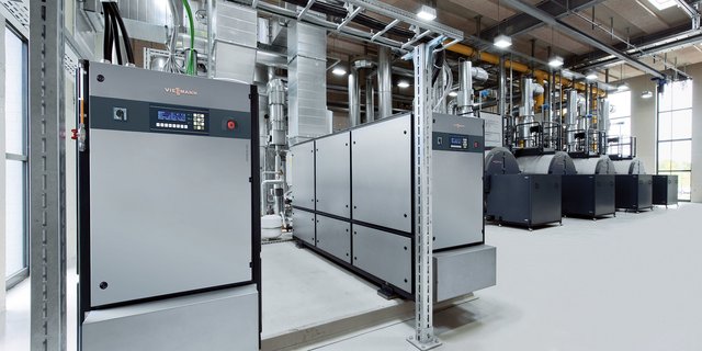 Eine moderne Industrieanlage mit mehreren großen Maschinen und einem hellen, offenen Raum, der durch große Fenster beleuchtet wird.