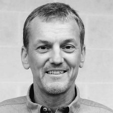 Der Mann trägt ein helles Hemd und hat einen freundlichen Gesichtsausdruck, der Wärme und Offenheit ausstrahlt.