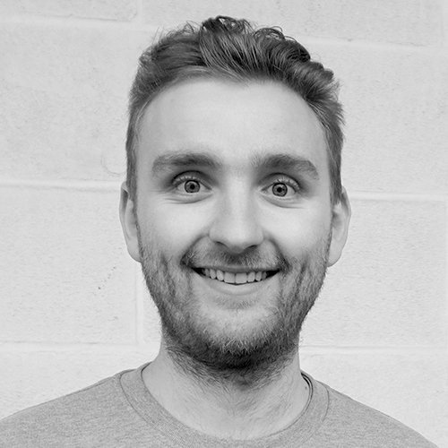 Der Mann trägt ein graues T-Shirt und hat einen freundlichen Gesichtsausdruck, der Freude ausstrahlt.